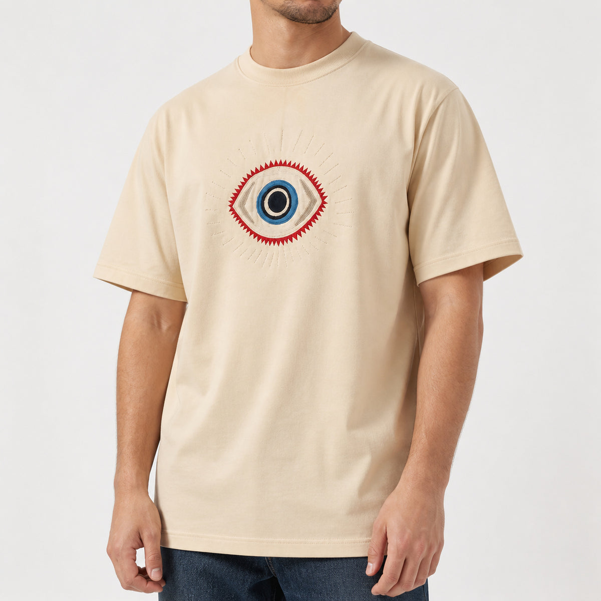 Man in the beige guardian eye embroidered t-shirt, front view
